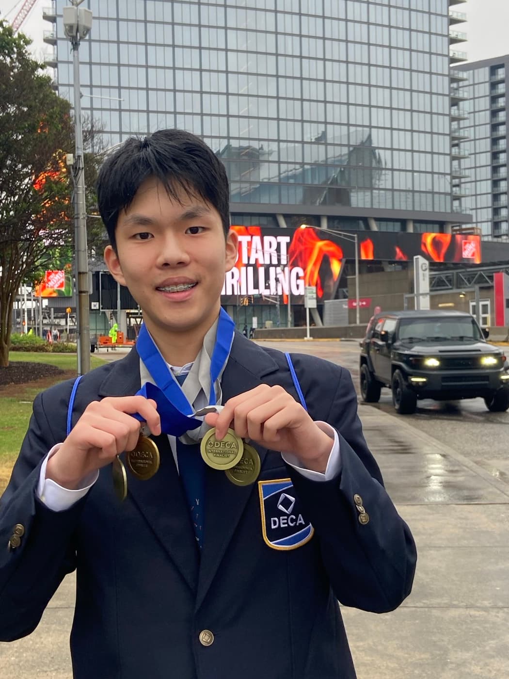 Dylan Hu holding his DECA ICDC International Finalist medals